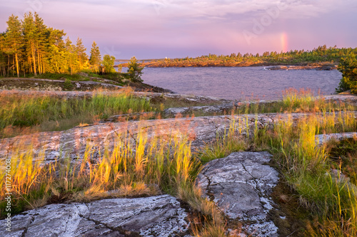 Bright rays of dawn sun refracted in the front of storm clouds forming a colorful rainbow,  Russian, Karelia, Ladoga lake photo