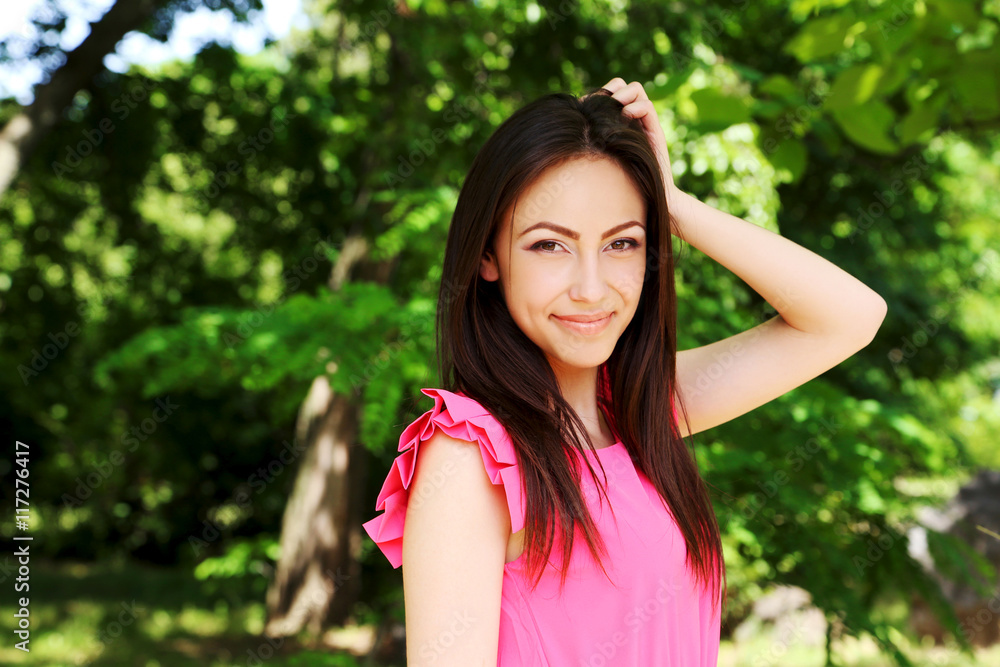 Young beautiful woman in pink dress standing in the park Young beautiful woman in pink dress standing in the park