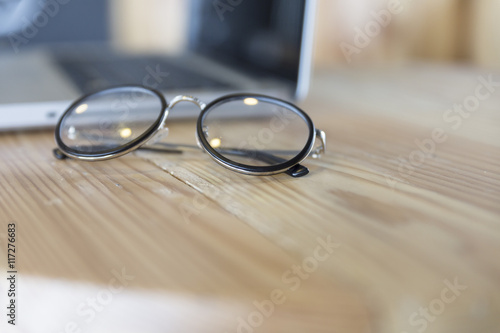 eyeglasses with laptop computer notebook on wooden desk