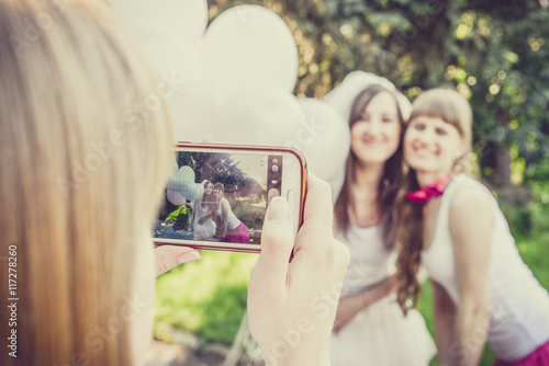 Beautiful bride and happy bridesmaids celebrating hen-party.Happy young hipster girls having fun at bridal shower, wearing colorful fluffy skirts and white t-shirt outdoors in city park on a sunny day