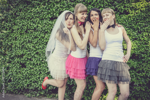 Beautiful bride and happy bridesmaids celebrating hen-party.Happy young hipster girls having fun at bridal shower, wearing colorful fluffy skirts and white t-shirt outdoors in city park on a sunny day