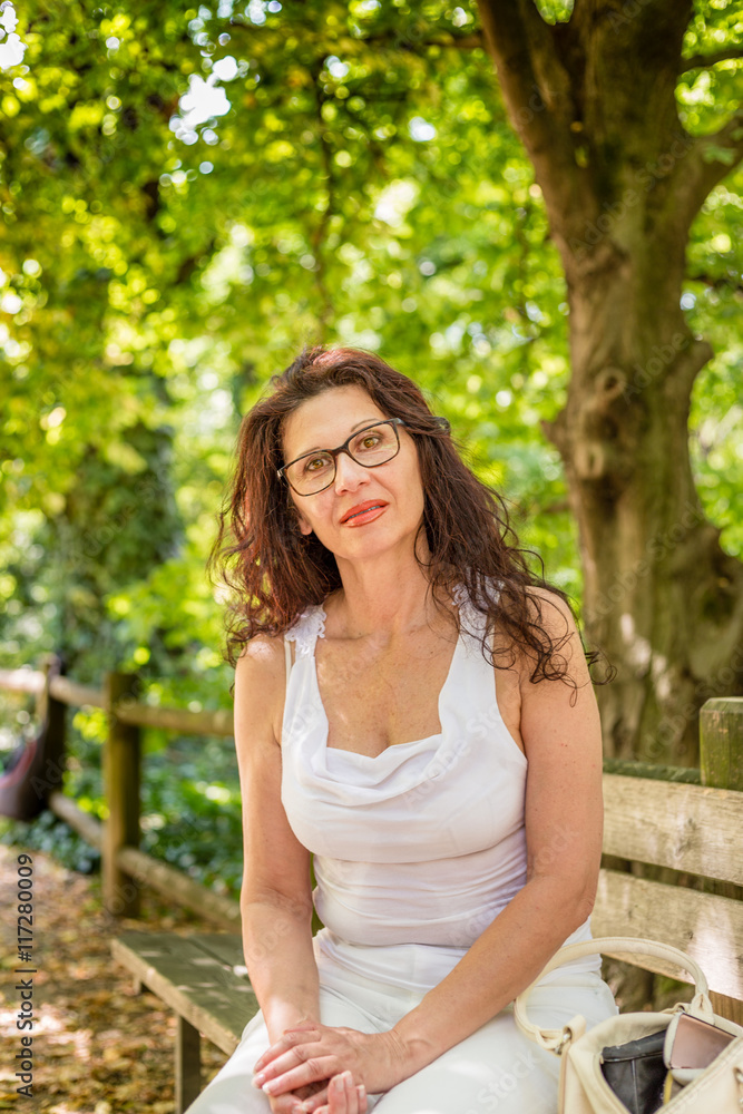 charming woman sitting on park bench charming woman sitting on park bench