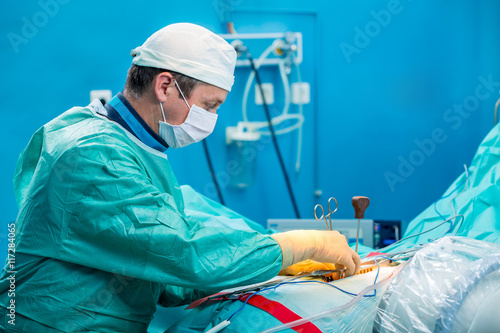 Young orthopedic surgeon operating the injured human spine.