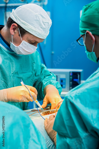 Orthopedic surgeons in teamwork performing surgery on human spin