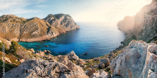 View of one of the most beautiful bays of Cap de Formentor at sunrise with azure water, wild beach, mountains and stones, Mallorca, Spain