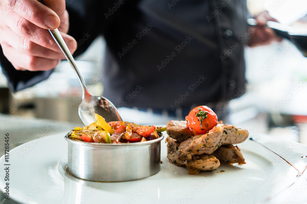 Foto Stock Koch oder Küchenchef beim Anrichten von Essen, ein Gericht mit  Fleisch und Gemüse | Adobe Stock