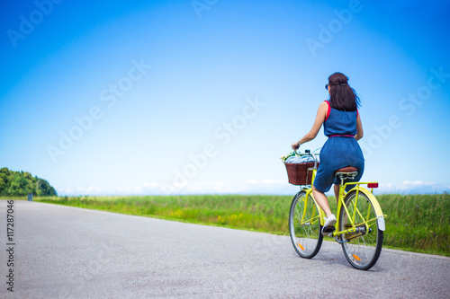 travel concept - back view of woman riding vintage bicycle with