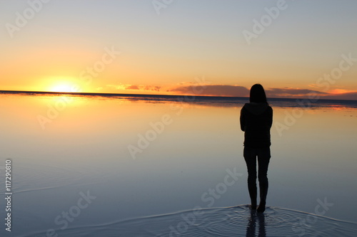 ウユニ塩湖の鏡張りと夕日を眺める人