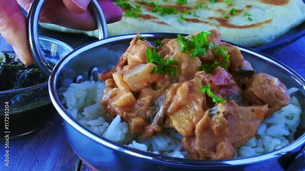 Indian woman serve a traditional Indian butter chicken curry with basmati rice. Food background. Indian woman serve a traditional Indian butter chicken curry with basmati rice. Food background.