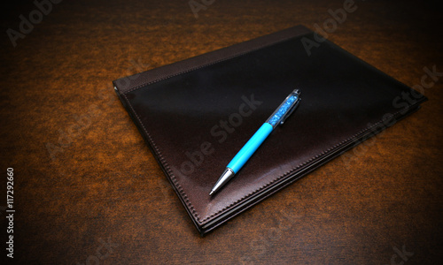 notebook and pen over a wooden background