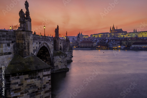 Charles Bridge in the city of Prague during the sunset with magic red sky.