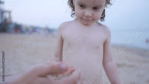 Child Playing on the Beach while Father Show how Sand Pours from Hands