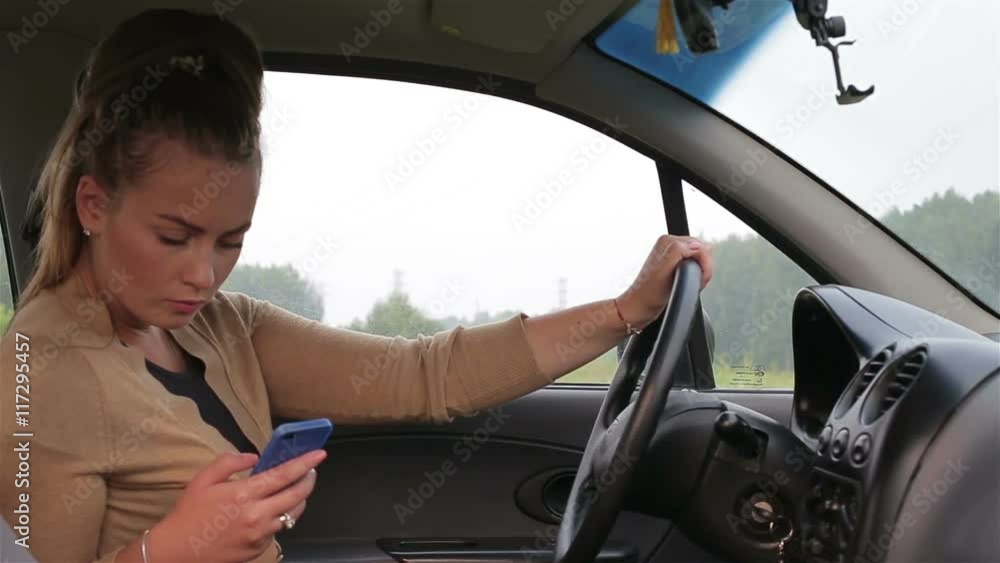 Young girl sitting behind the wheel car use smartphone Young girl sitting behind the wheel car use smartphone