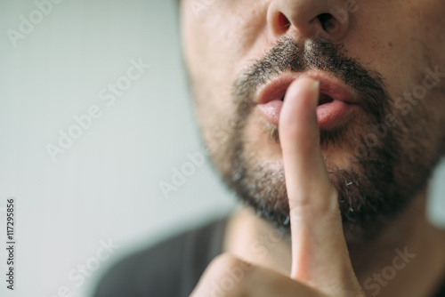 Finger on lips, man gesturing shhh sign
