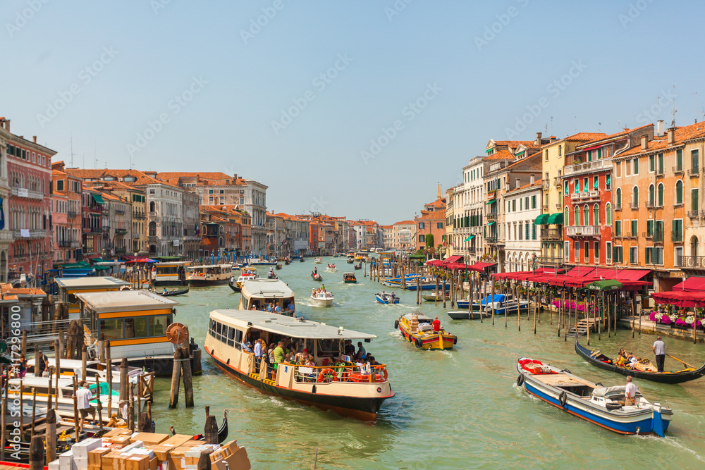 Grand Canal in Venice in the afternoon with a lot of gondolas, boats, ferries, etc. Brightly colored houses and Palazzo of Venice with facades in different styles. Italy