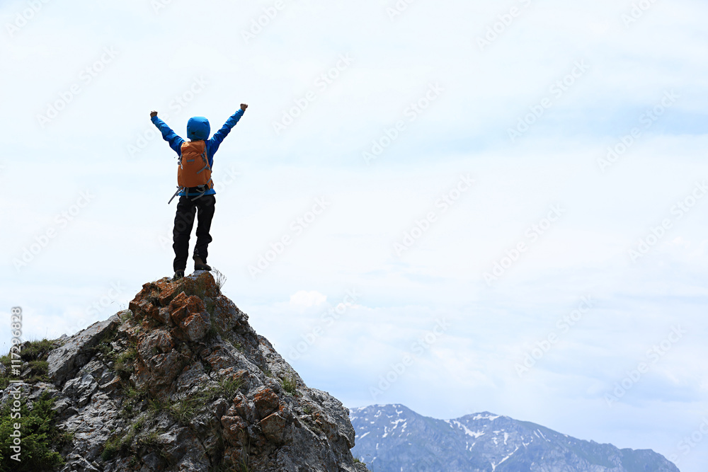 Obraz premium successful young woman backpacker open arms on mountain peak