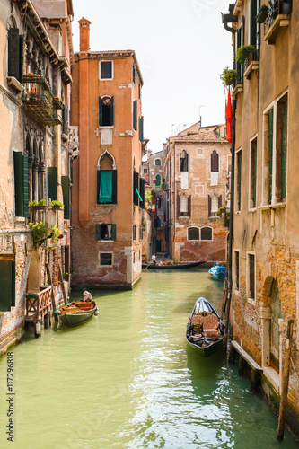 View from the bridge on the small canals in Venice. Beautiful scenic street with water and boats. Bright colorful houses on the water. Italy.