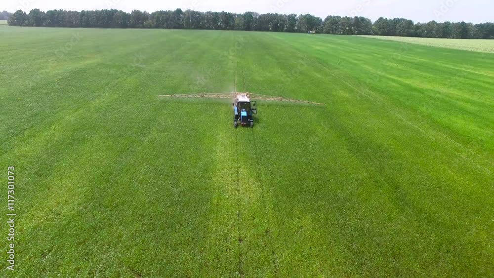Tractor in a field spray the plants with pesticides. aerial survey Tractor in a field spray the plants with pesticides. aerial survey
