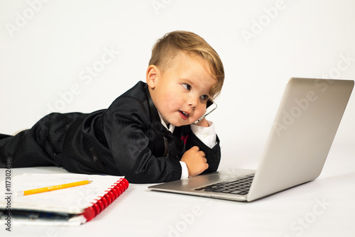 a child in the role of office manager with laptop and phone