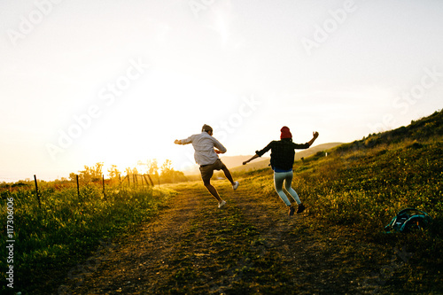 Couple leaping in mid air in field
