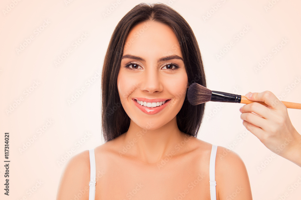 Portrait of cute cheerful girl doing maquillage with brush of po Portrait of cute cheerful girl doing maquillage with brush of po