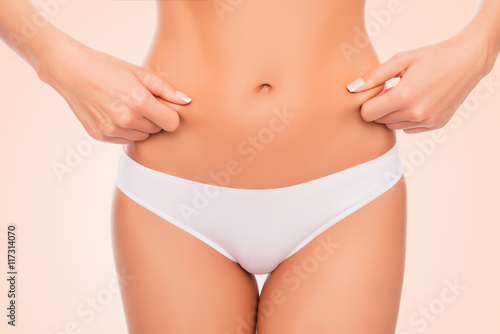 Close up portrait of fit woman checking fat on her belly