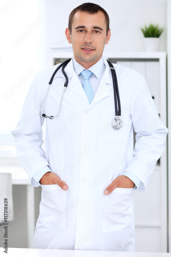 Friendly male doctor in the hospital office. Ready to examine and help patients. High level and quality medical service concept. Friendly male doctor in the hospital office. Ready to examine and help patients. High level and quality medical service concept.