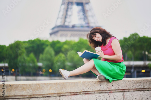 Young girl reading a book near the Eiffel tower