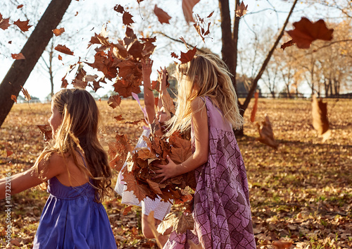 Young girls children kids playing running in fallen autumn leave