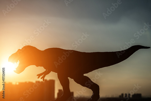 silhouette of tyrannosaurus and buildings in sunset time
