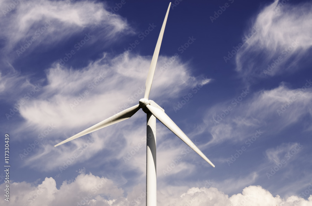wind turbine against partly cloudy blue sky wind turbine against partly cloudy blue sky