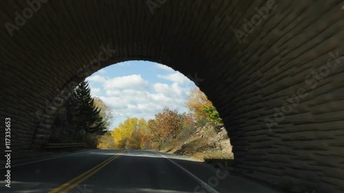 Driving on Eagle Lake Road passing under Acadia All American Road, in Acadia National Park in Autumn.