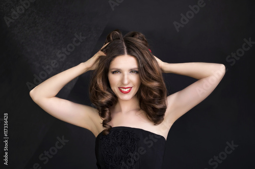 Portrait of beautiful woman in black dress with curly hair - isolated on black background. © Victoria Key