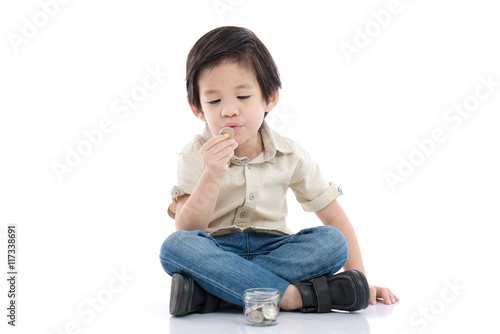 Cute Asian child saving money in glass bottle
