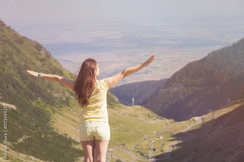 Trekking woman on the peak of Fagaras Mountains, above Transfagarasan highway. Young woman standing on a mountain top with outstretched arms. Vintage look Trekking woman on the peak of Fagaras Mountains, above Transfagarasan highway. Young woman standing on a mountain top with outstretched arms. Vintage look