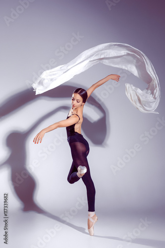 Fotografie Ballerina in black outfit posing on toes, studio background.