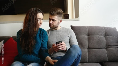 Beautiful young woman and her husbund staying at home, man using his mobile phone. photo