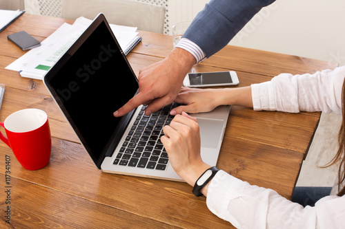 Businessman supervising secretary work on laptop, closeup of hands, unrecognizable