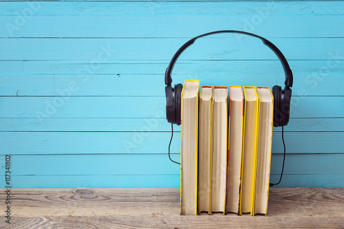 Audio book concept, yellow books and headphones over blue backgr