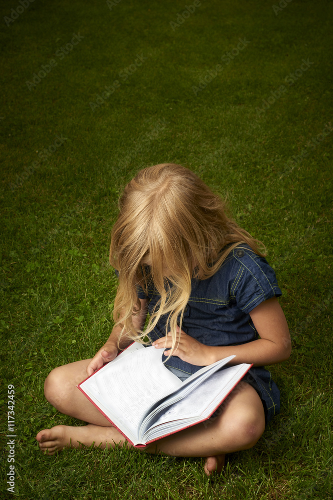 Cute Little Blond Girl Reading Book Outside on Grass Cute Little Blond Girl Reading Book Outside on Grass