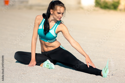 Athletic woman stretching exercise training fitness on a beach summer