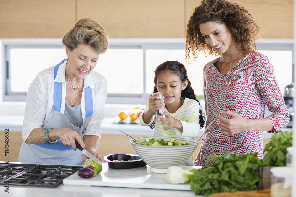 Senior woman with daughter and granddaughter preparing food in kitchen Senior woman with daughter and granddaughter preparing food in kitchen