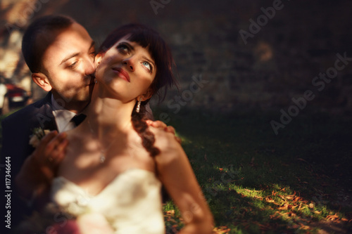 Groon kisses delicate bride's neck tender hugging her from behin
