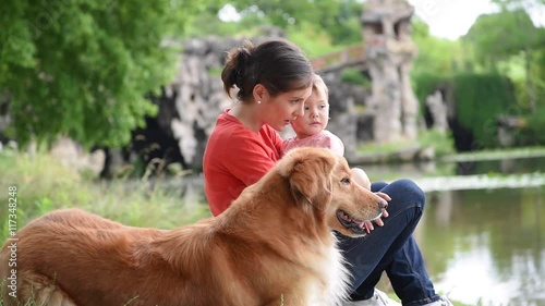 Woman and baby girl playing with golden retriever dog