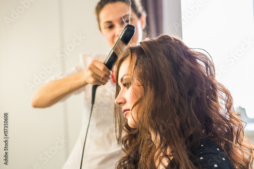 Close up of stylist's hand using curling iron for hair curls.