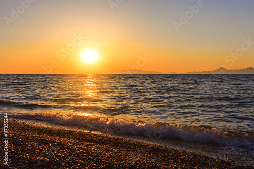 Pebble beach and sea at sunrise or sunset. Toned