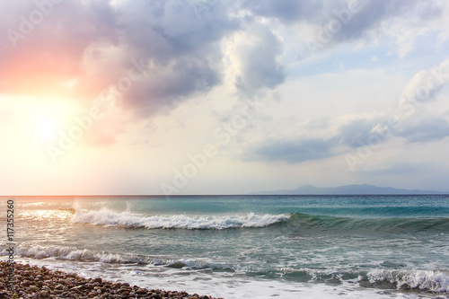 pebble beach and sun with cloudscape