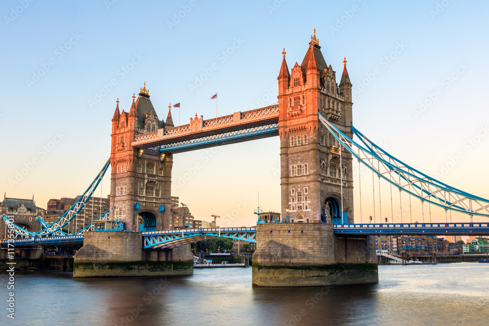 Fototapeta premium Tower Bridge in London at sunset, casting a orange light on part of the bridge
