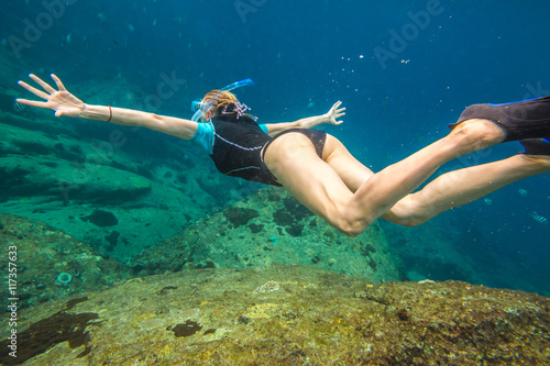 Young woman free diving in the blue waters of the popular Similan Islands in Thailand, one of the tourist attraction of the Andaman Sea.