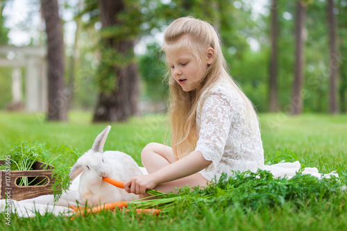 Little girl playing with white rabbit outdoor
